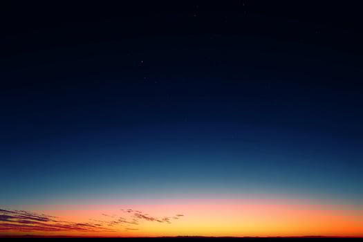 Realistic evening twilight sky with vibrant orange blending softly into dark blue over the calm horizon photo
