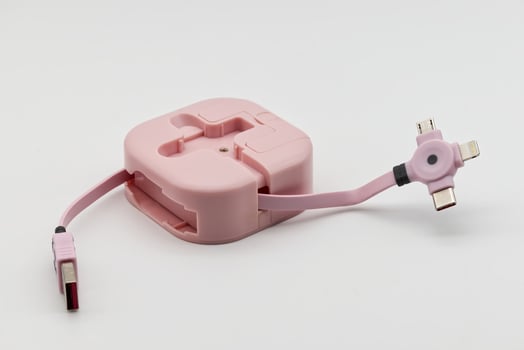 A pink retractable multi-charging cable with various connectors lies on a clean white background, ready for use. photo