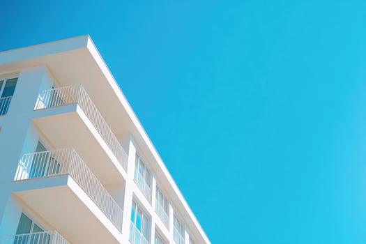 A white building with balconies and a blue sky photo