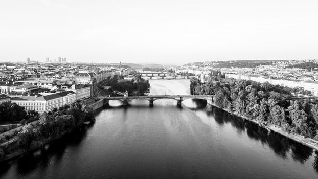 Aerial view of the Vltava River winding through Prague, showcasing the National Theatre and several bridges. The landscape features lush trees along the riverbank and historical architecture. photo
