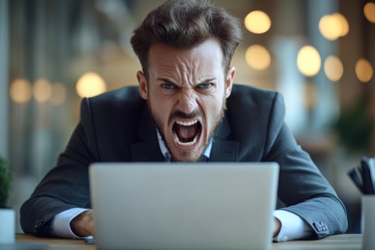 A man in a suit yelling at his laptop photo