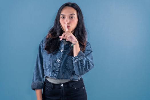 Indonesian Asian woman wearing blue jeans jacket signaling for silence photo