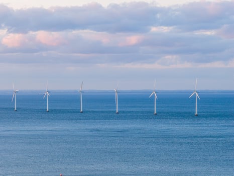 Six wind turbines stand in calm blue waters under a partly cloudy sky with pink hues, showcasing sustainable energy infrastructure in Copenhagen, Denmark. photo