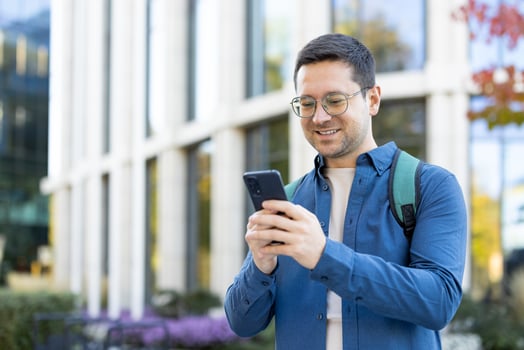 Man smiling using smartphone outdoors photo