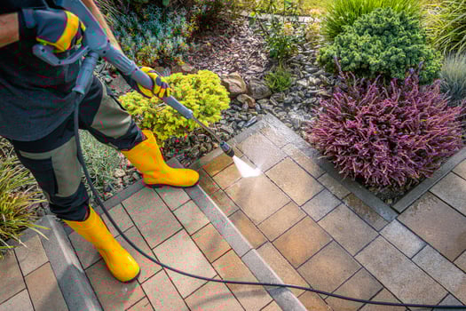Person Cleaning Paver Stones in Garden With Pressure Washer on Sunny Day photo