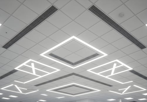 Geometric ceiling design in a modern office with detailed lighting pattern and air vents, symmetrical and clean environment, no people present photo