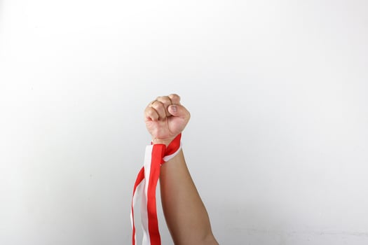 Clenched hand winning gesture with red white ribbon photo
