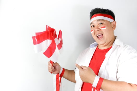 A man holding a singapore flag and wearing a headband photo