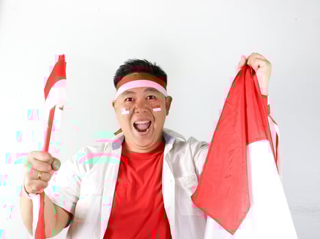 Cheerful Indonesian guy celebrating indepedence day with flags on his hand photo