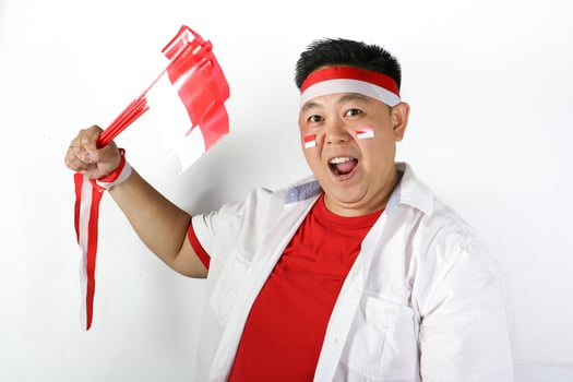 A man with a red and white striped headband holding a red and white flag photo