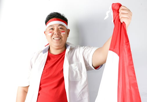 Smiling Indonesian man holding a red and white Indonesian flag photo