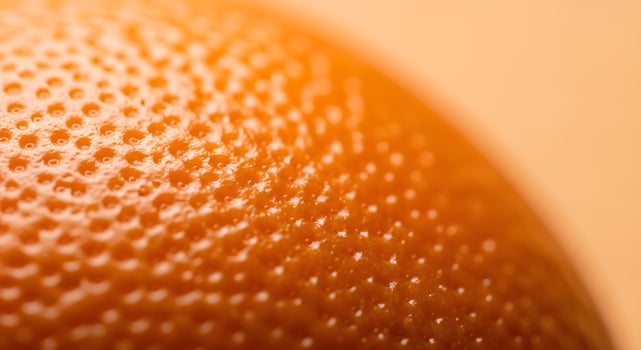 Close-up of orange peel surface with soft natural light and clear pores, ultra detailed, crisp edges, noise free, pastel orange background, fresh citrus skin texture photo
