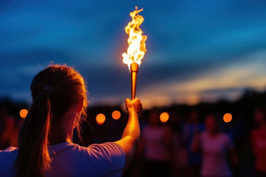 Woman holds torch night event crowd sunset photo