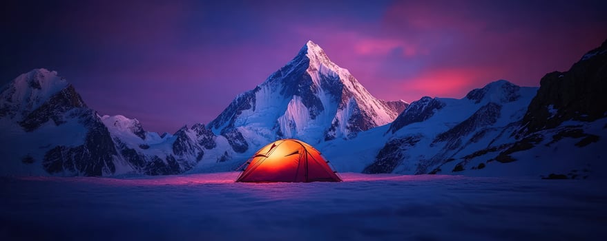 Illuminated tent in snowy mountain range at sunset photo