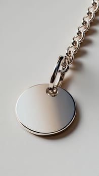 Blank silver disc pendant chain close-up, beige background photo