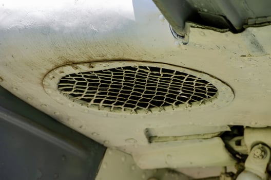 A white vehicle with a mesh grill on the hood. The grill is dirty and has a lot of rust photo