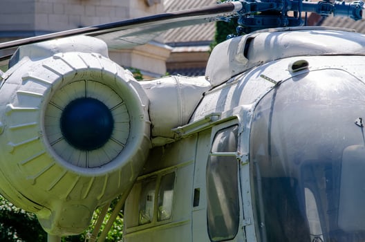 A white helicopter with a blue engine. The engine is on the left side of the helicopter. The helicopter is parked in a grassy area photo