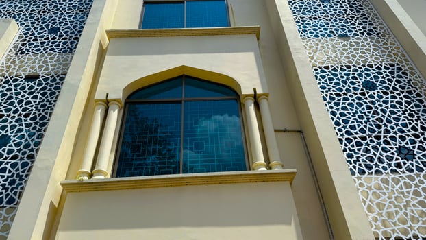 Exterior features yellow structure with Islamic geometric patterns and blue glass windows in high resolution photo