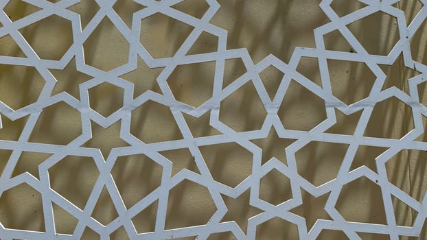 Abstract white geometric star pattern on yellow wall exhibits the islamic art style photo