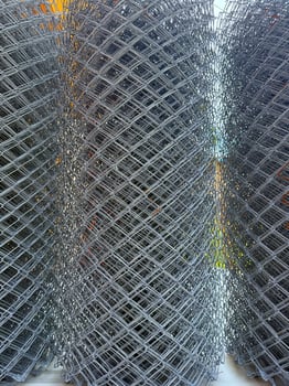 Stacked rolls of galvanized chain link fencing form an industrial texture in this high resolution photo