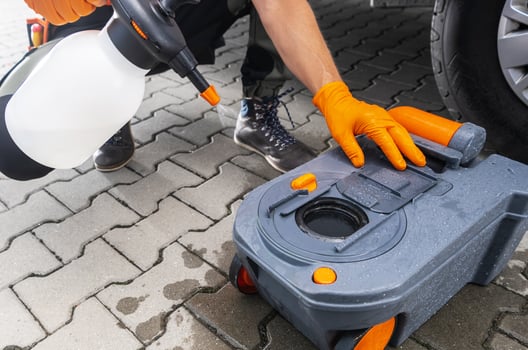 Hand Cleaning Toilet Cassette Being Used on a Camper Van Vehicle in a Parking Lot photo