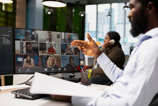 Close up of team leader reviewing paperwork while on videocall meeting, talking with remote working staff members. Supervisor at office desk reading files during online teleconference photo