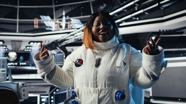 Jolly astronaut waves hand during videocall with Earth command center, documenting results from space experiments. Cosmonaut salutes ground center team, sharing research observations photo