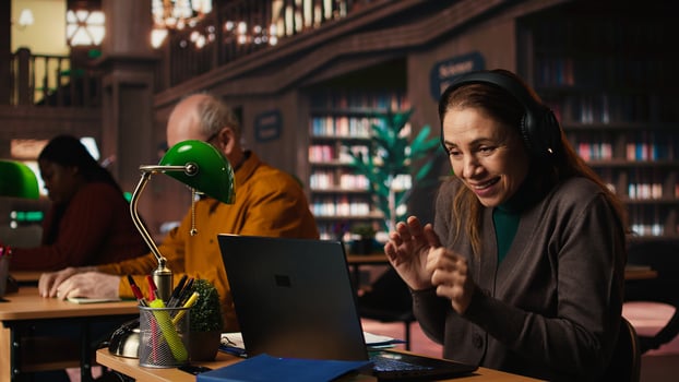 Woman listens to loud music on headset and disturbing other people in the library, senior man asking her to keep the volume low, breaking the library rules. Careless person singing. photo