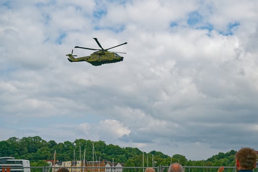Military helicopter flying low over crowd under blue sky with clouds in flensburg photo