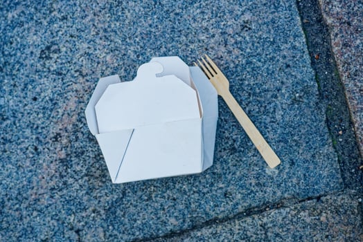 Paper food box and wooden fork on stone street pavement in copenhagen CPH photo