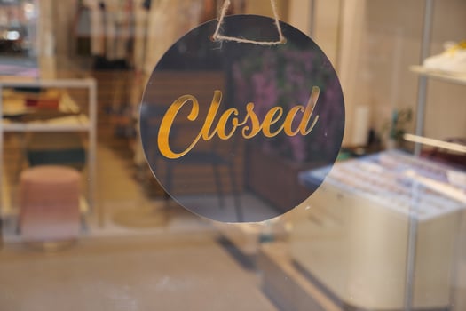 Closed sign hangs in shop window during business hours photo