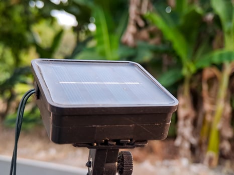A solar panel battery pack sits outdoors, promising clean energy with foliage in the background. photo