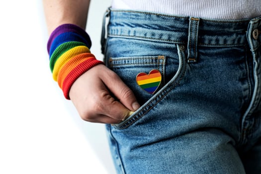 Person wearing rainbow wristband and rainbow heart pin on denim jeans photo