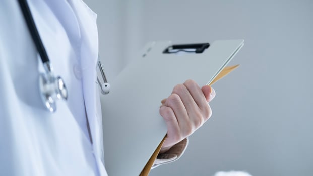 Doctor in white lab coat with stethoscope holding clipboard and folder, symbolizing medical documentation, patient confidentiality, and healthcare service. photo