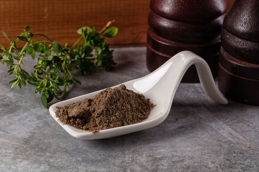 A scoop of powder sitting on a table next to a bottle of herbs photo