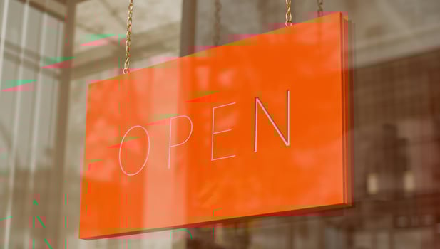 An orange sign hanging from a window that says open photo