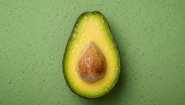 Fresh Avocado Half with Seed on a Wet Green Background, Healthy Food Concept. photo