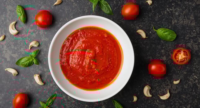 Fresh Tomato Sauce in a White Bowl with Basil and Garlic on Dark Background. photo