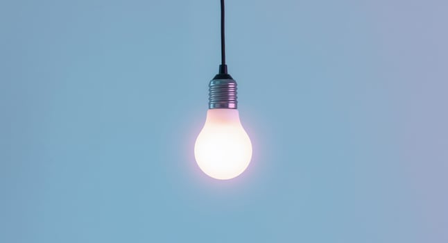 A Bright Idea. Lit Light Bulb on a Pale Blue Gradient Background, Simple and Clean photo