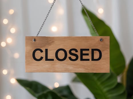 A Wooden Sign Hanging From a Chain Displaying the Word CLOSED in Bold Letters. photo