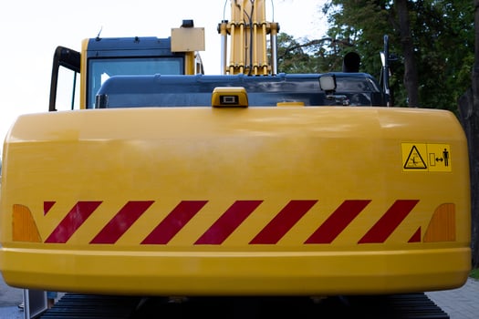 Rear of excavator slewing mechanism with warning signs about overhang of body. Safety when working with excavator. Reflective elements and signs to warn about rotation of excavator body photo