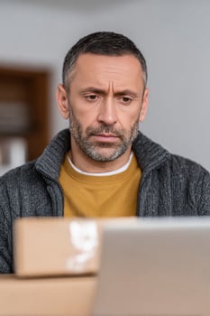 A contemplative Middle Eastern man examines online shopping boxes, embodying Singles Day anticipation and Cyber Monday decision making intrigue photo