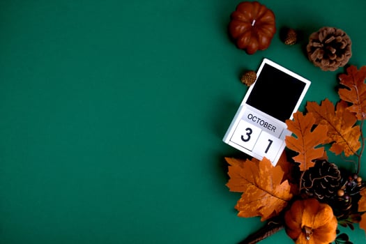 On a green background lies a calendar with the date of Halloween, surrounded by autumn paraphernalia.Space for text. photo