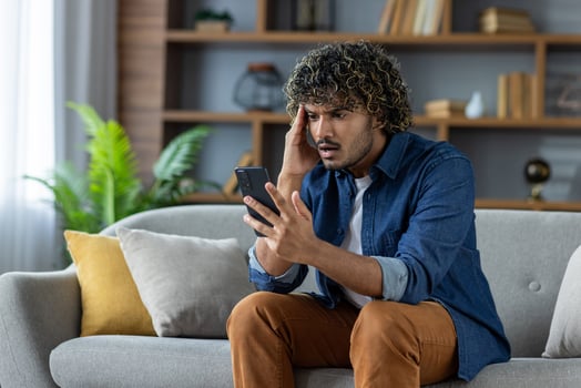 Stressed man using smartphone on couch photo