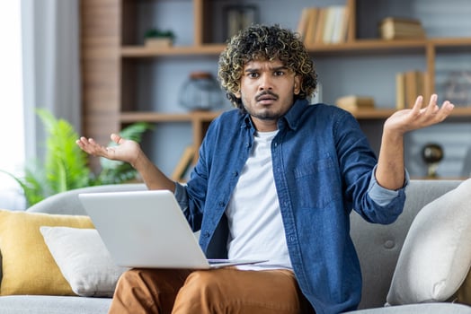 Confused man with laptop looking puzzled photo