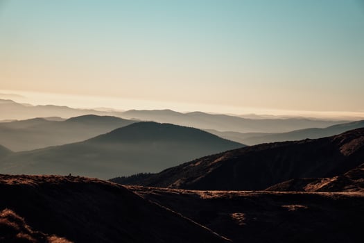 Golden hour view of layered mountain ridges fading into mist with soft warm light and gentle gradients in the sky creating a dreamy peaceful landscape perfect for nature lovers and travel inspiration photo