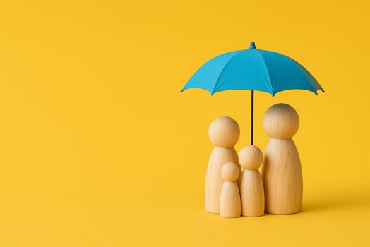 Four wooden peg figurines under a blue umbrella on yellow background symbolizing family security and insurance coverage photo