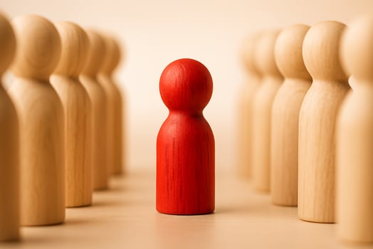 A red figurine in the center between two groups of natural figurines symbolizing mediation or central leadership. photo