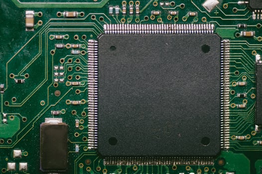 A black chip on a green circuit board photo