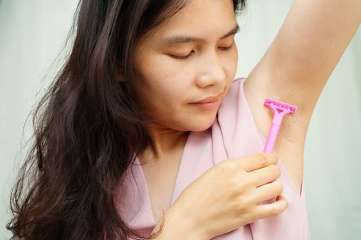 Asian young woman shaving armpit hair clean removal with razor after shower. photo